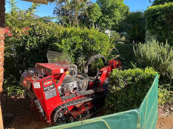 grinding stump in the garden bed with safety barricades